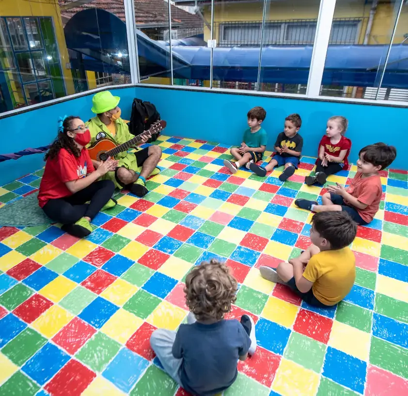 Sala de aula ampla e organizada, com mesinhas e cadeiras infantis coloridas