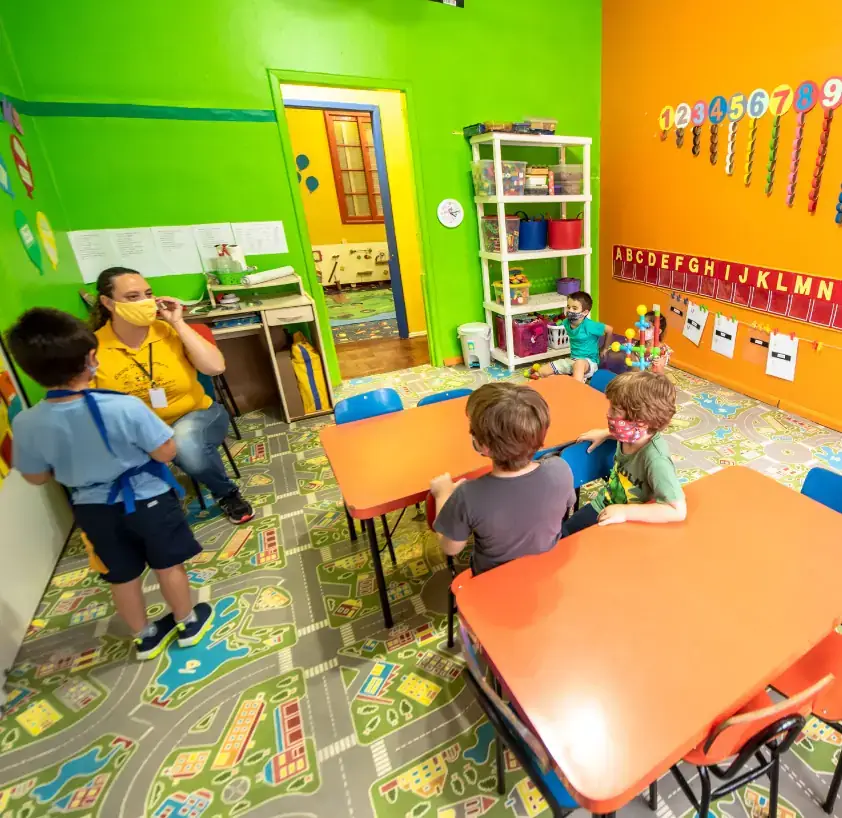 Sala de aula colorida com painéis decorativos e materiais pedagógicos nas prateleiras